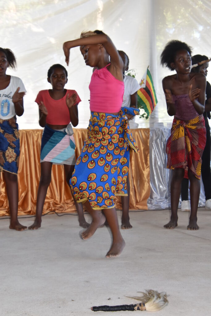 Children performing a dance routine on stage during a talent show at an old age home.