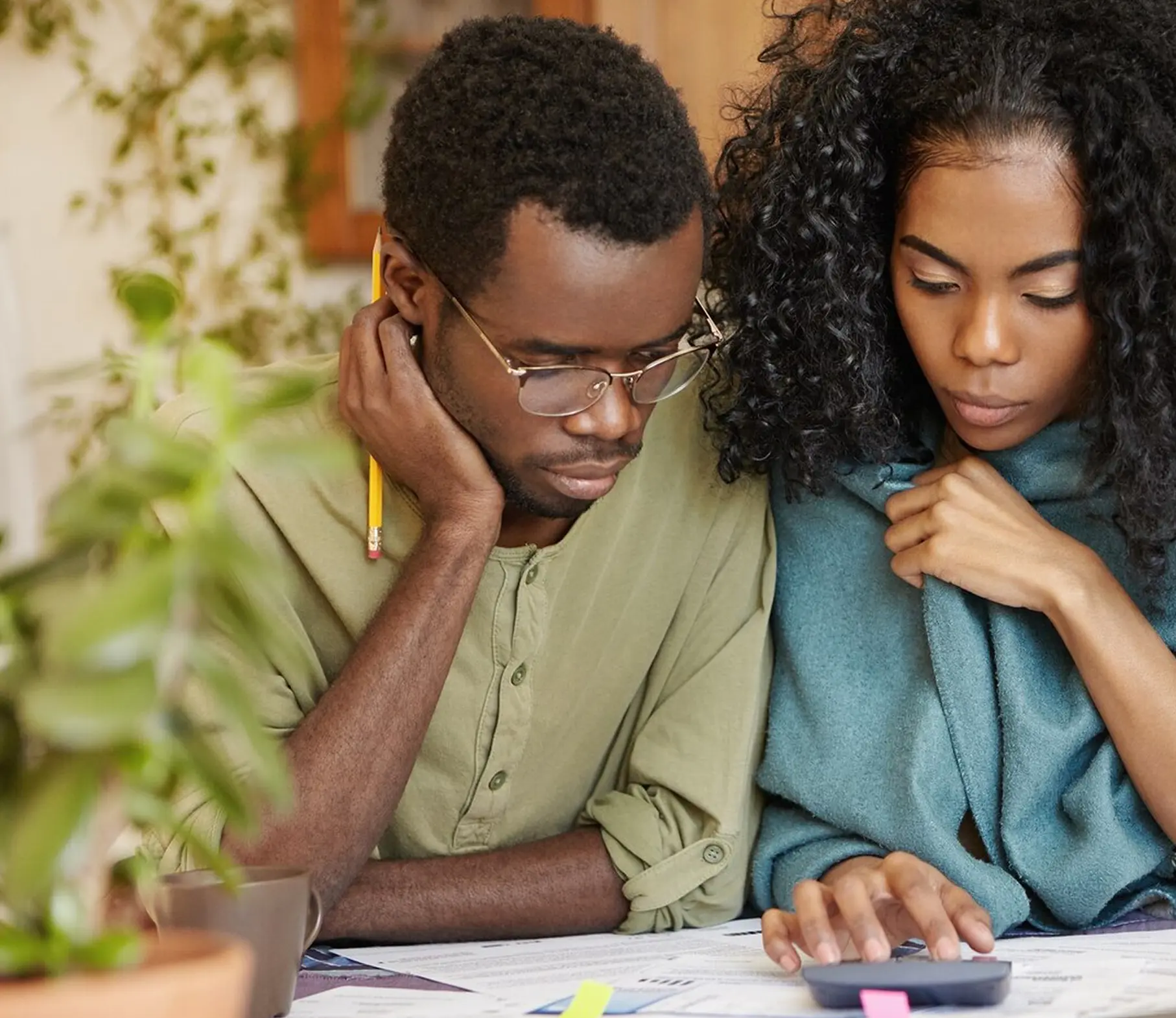 A man and woman look over documents, concentratingly, while sat at a table.