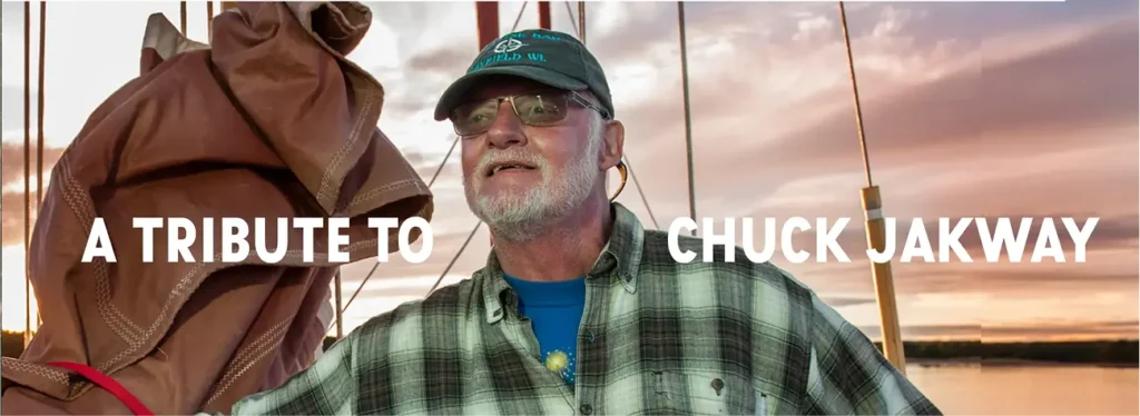 Banner reading ‘A tribute to Chuck Jakway’ featuring an older man wearing a green plaid shirt and cap on a boat.