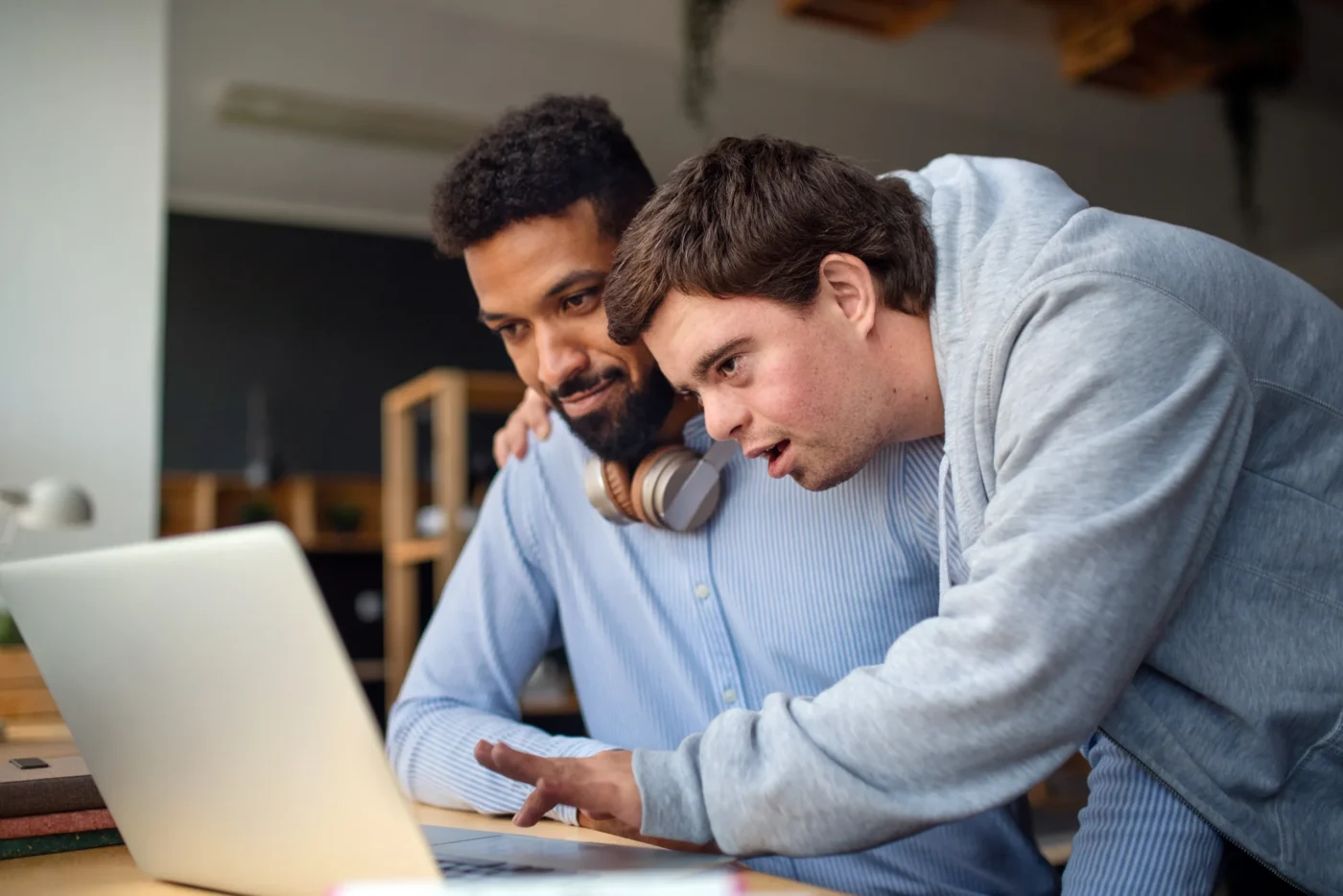 two-adults-using-laptop-computer-close-up Two people collaborating at a laptop, with one person leaning over and pointing at the screen while the other watches